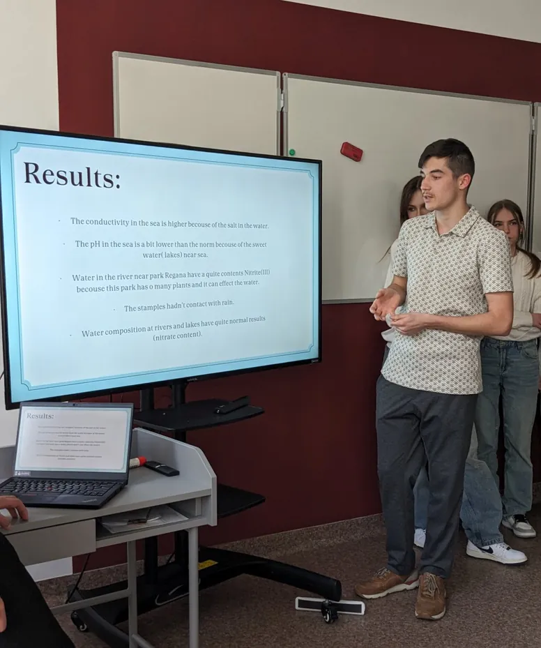 Uczeń przedstawia wyniki badań wody przy ekranie ze slajdem „Results”